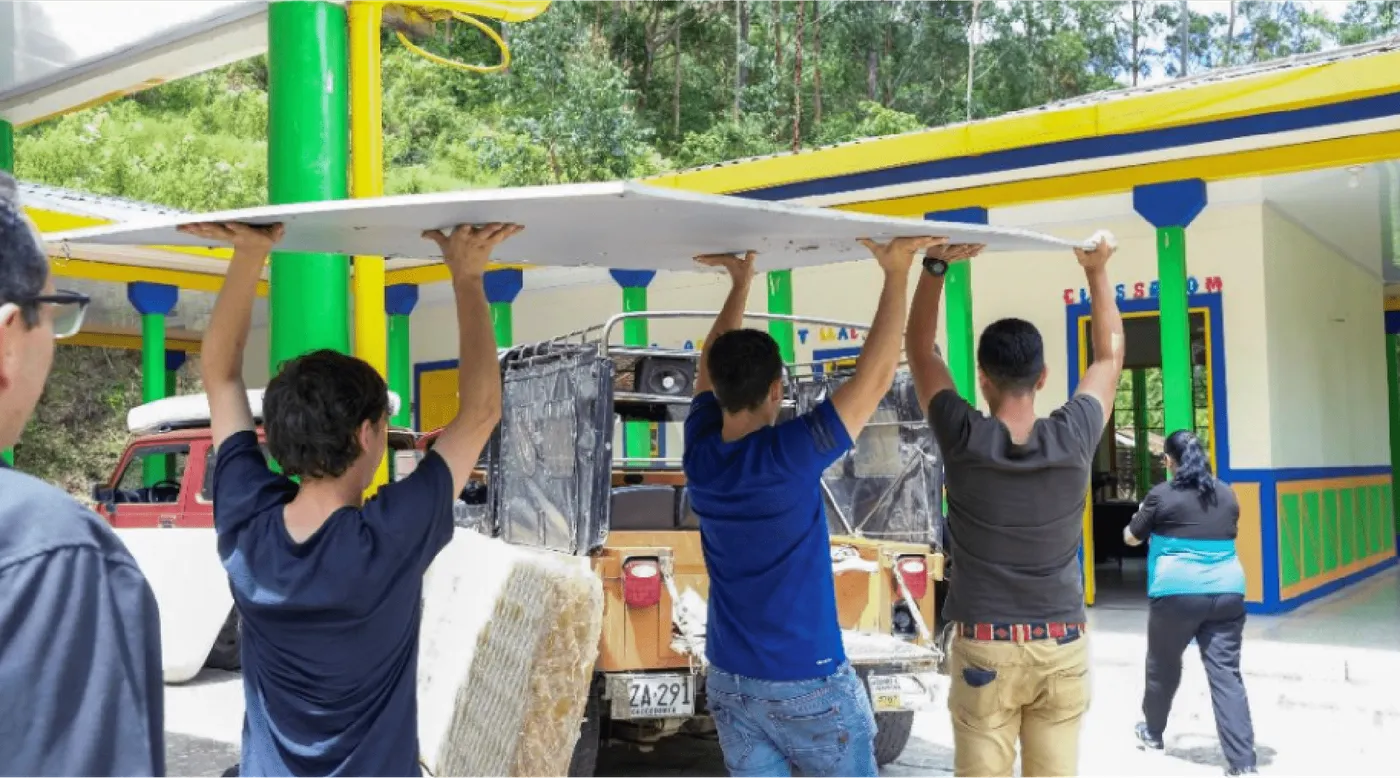 Voluntarios cargando materiales para la obra de una escuela rural
