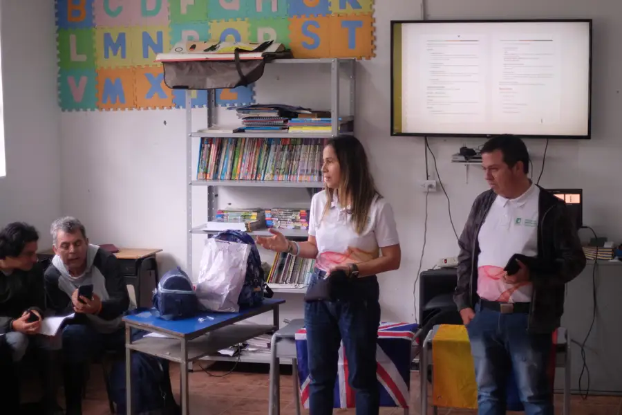 Taller comunitario en un aula con las banderas de Colombia y el Reino Unido