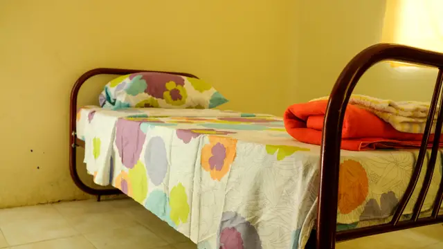 Una cama tendida con sábanas y cobijas nuevas, parte de la dotación entregada a una escuela rural