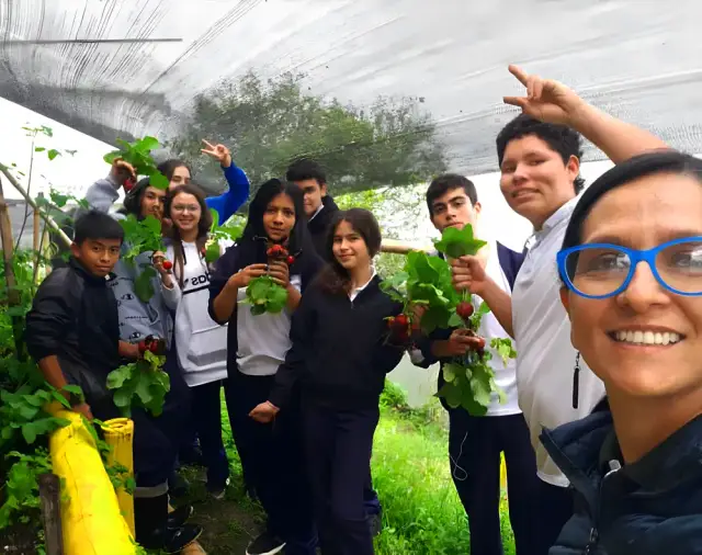 Estudiantes y su docente celebran la cosecha de rábanos en la huerta escolar