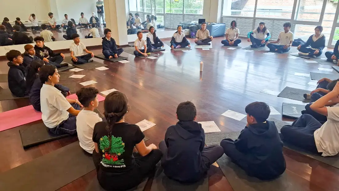 Círculo de meditación alrededor de una vela durante una sesión de yoga escolar