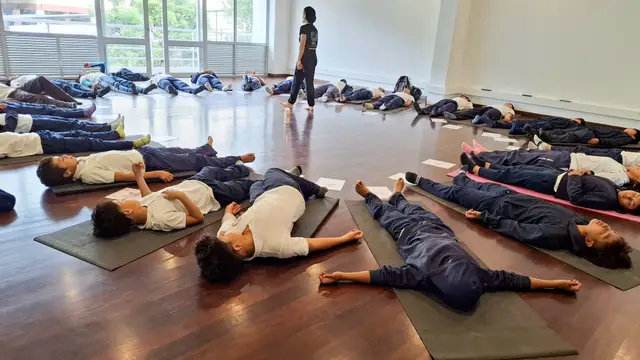 Estudiantes en relajación profunda sobre esterillas al final de la práctica